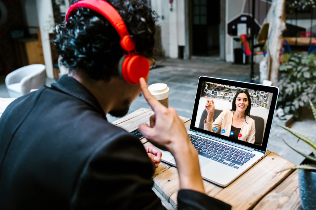 Man attending Online Hindi Courses, participating in a virtual class with headphones and video call on laptop.